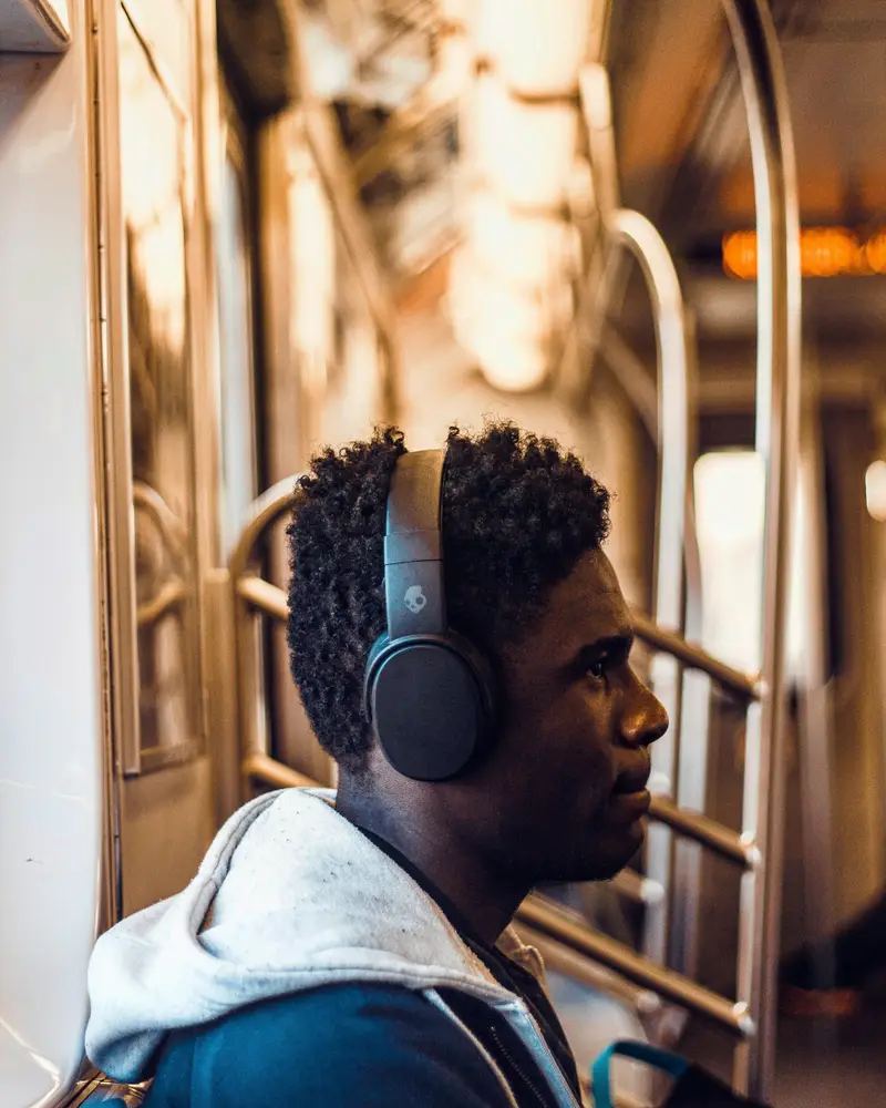 Persona con auriculares inalámbricos de diadema viajando en tren